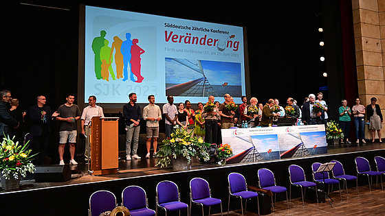 Fast überfüllte »Personalbühne« – die Konferenzmitglieder freuen sich über zwanzig »Neue« in verschiedenen Arten von Gemeindediensten und freuen sich mit sechs Personen, die Dienstjubiläen feiern.
