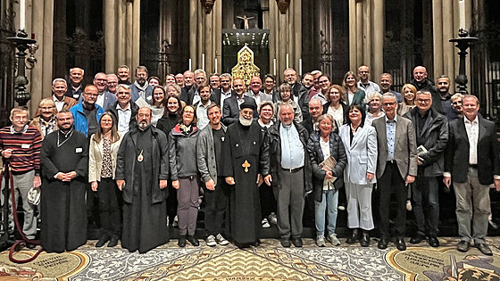 Vor sechs hohen tragenden Säulen in einer Kirche stehen rund 50 Personen, manche von ihnen in geistlichem Ornat. Werner Philipp, der für Deutschland zuständige Bischof der EmK, steht ganz hinten links.