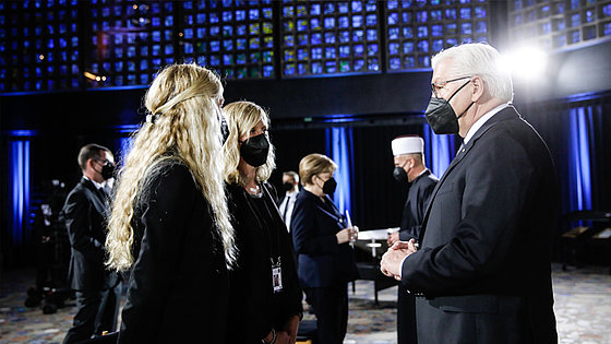Bundespräsident Frank-Walter Steinmeier (r.) vor dem ökumenischen Gottesdienst für die Verstorbenen der Corona-Pandemie in der Kaiser-Wilhelm-Gedächtniskirche in Berlin im Gespräch mit zwei Frauen.