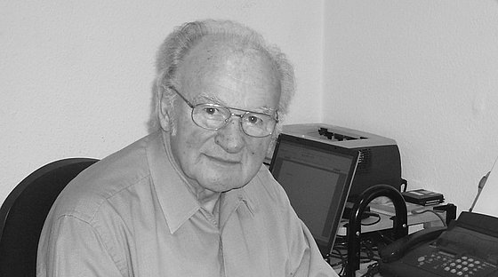 Pastor Kurt Scherer mit schütterem Haar im Alter von 69 Jahren. Brille tragend und mit einem hellblauen Hemd gekleidet schaut er nachdenklich-entspannt in die Kamera.