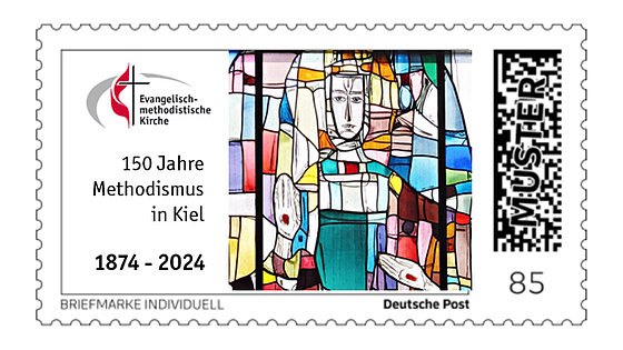 Eine Briefmarke im Querformat zeigt links oben das deutsche Signet der EmK, darunter den Text »150 Jahre Methodismus in Kiel 1874 – 2024«. Rechts daneben  das Fenster aus farbigem Glas. Deutlich treten ein Gesicht und 2 durchbohrte Hände hervor.