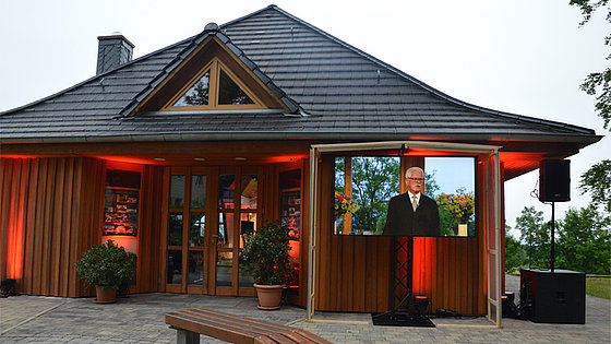 Drinnen Technik und Akteure, draußen Sitzgelegenheit mit Großbildschirm. Das Übertragungszentrum der Ostdeutschen Jährlichen Konferenz im »Backhaus« der Begegnungs- und Bildungsstätte Schwarzenshof. 