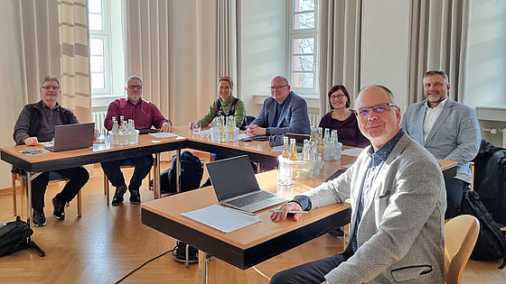 In einem hellen Raum sitzen zwei Frauen und fünf Männer an U-förmig gestellten Tischen. Sie bilden die Steuerungsgruppe für die in Deutschland anstehenden und umzusetzenden Veränderungsprozesse für die Evangelisch-methodistische Kirche.