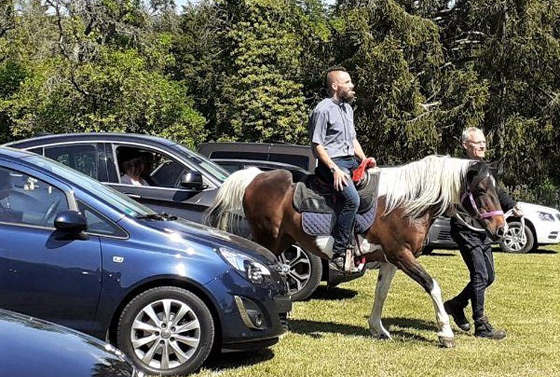 »Gottesdienst mit Pferdestärken« zu Himmelfahrt an der Begegnungs-und Bildungsstätte Schwarzenshof. Pastor Matthias Zieboll reitet ganz nach der Art John Wesleys auf einem Pferd zum Autogottesdienst ein.