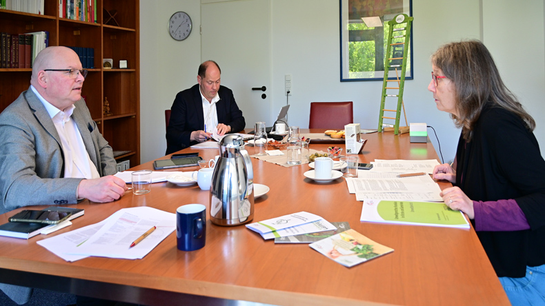 »Prüfungsgespräch«: Die Auditorin Carmen Ketterl im Gespräch mit dem Leiter der Kirchenkanzlei, Jörg Hammer. Im Hintergrund Stefan Weiland, der für Umweltberatung und schöpfungsgemäßes Handeln in Kirche und Gemeinde zuständig ist.