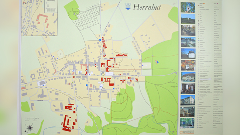Ortskarte der Herrnhuter Siedlung: Waagerecht quert die Hauptstraße den Ort. Rechts und links zweigen Ortsstraßen ab. Rot hervorgehoben sind geschichtlich wichtige Gebäude der Brüdergemeine, die an der rechten Seite in einer Legende erklärt werden.