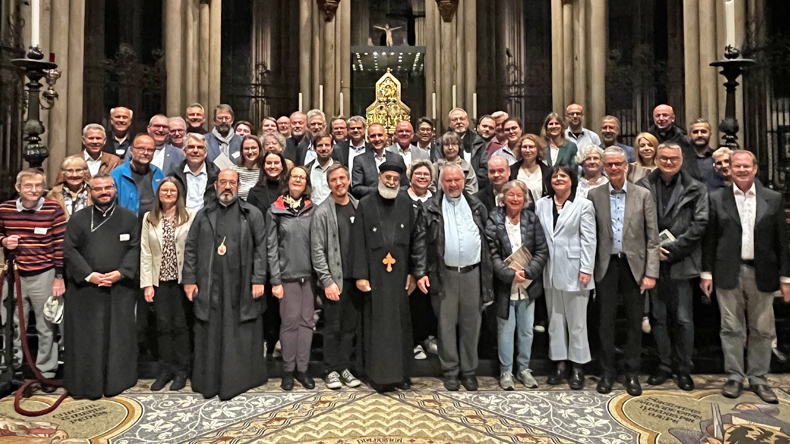 Vor sechs hohen tragenden Säulen in einer Kirche stehen rund 50 Personen, manche von ihnen in geistlichem Ornat. Werner Philipp, der für Deutschland zuständige Bischof der EmK, steht ganz hinten links.
