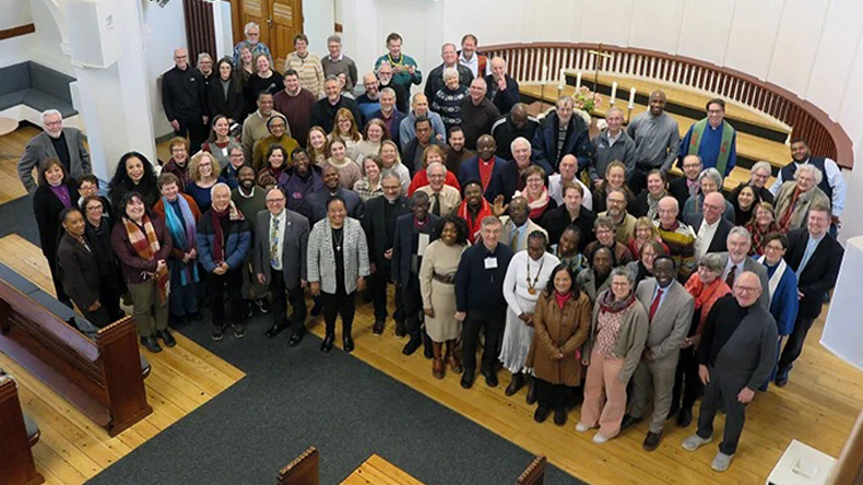 Das Foto zeigt das Innere der Jerusalemkirche in Kopenhagen mit etwa 80 Personen, die sich im vorderen Teil der Kirche zum Gruppenbild aufgestellt haben. Sie sehen hoch zur Kamera.