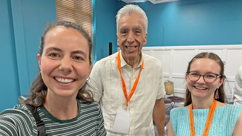 Lea Schmidt (links, gestreiftes Shirt), Bischof Ruben Saenz Jr. (Mitte, weißes Hemd) und Imke Sewing (rechts, hellblaues Oberteil) stehen bei der Global Young People’s Convocation in Dublin zusammen. Alle drei lächeln in die Kamera.
